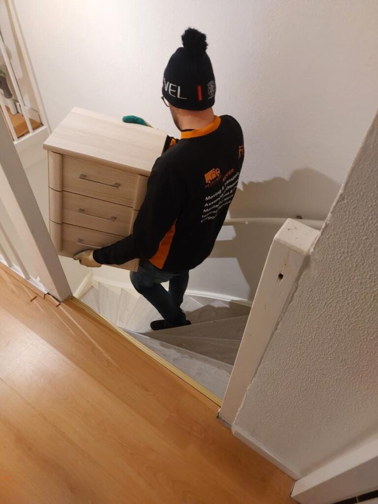 Mover carefully carrying a cabinet down the stairs using a moving checklist to tick off pdf to stay efficient